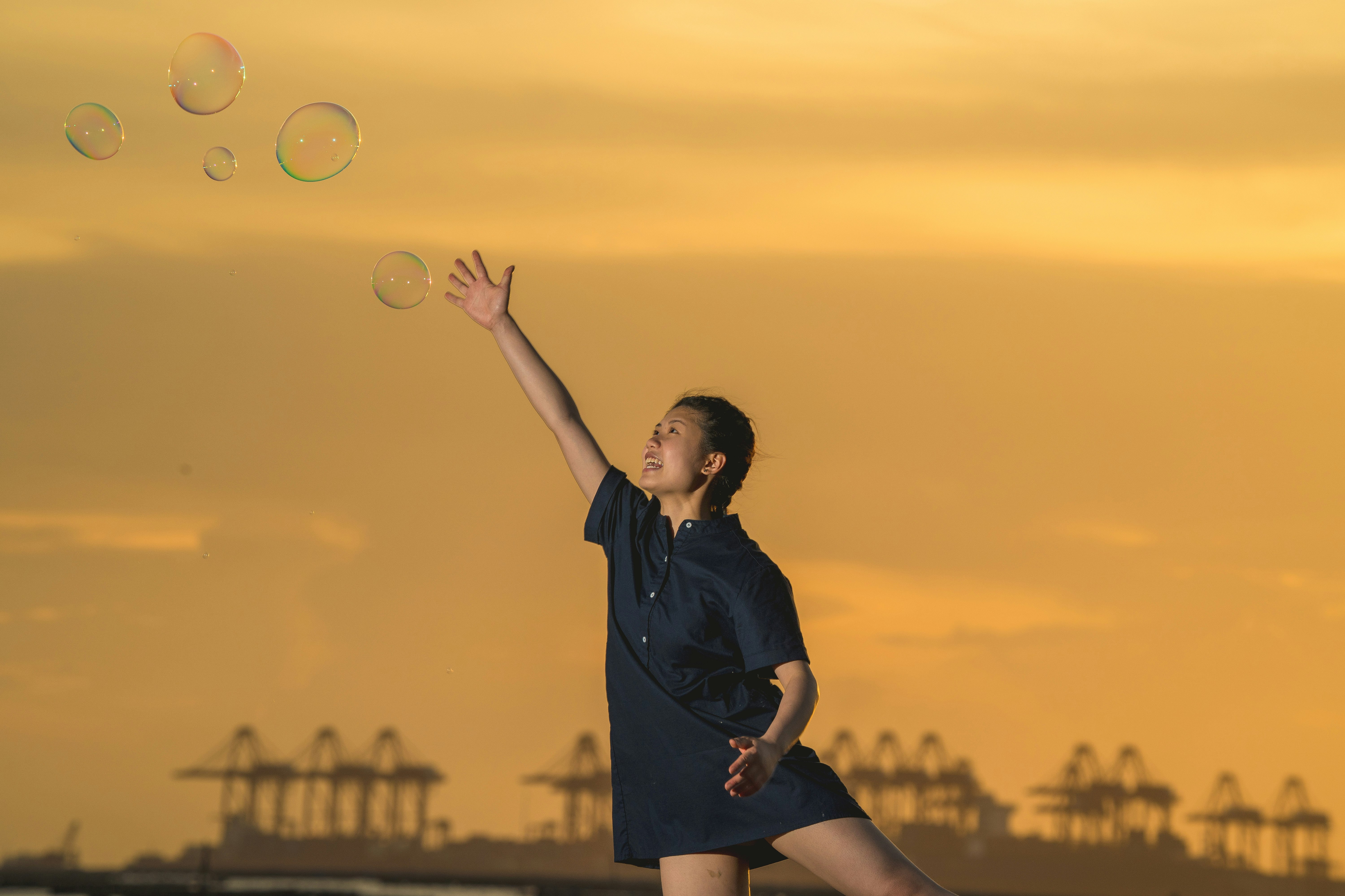 woman in black dress holding bubbles during sunset